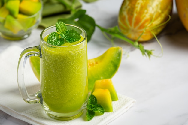 glass of melon juice put on white marble floor