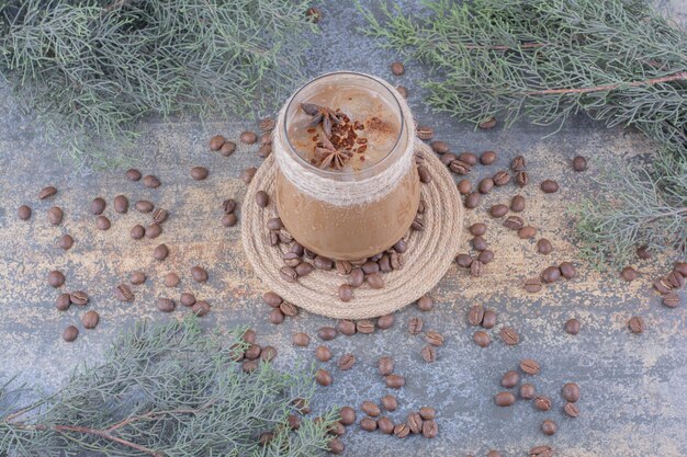 Glass of milk coffee with coffee beans on marble surface. High quality photo