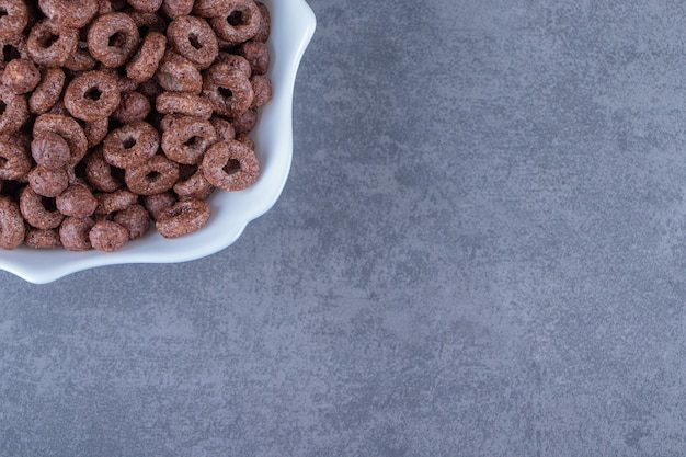 A glass of milk next to corn rings in a bowl , on the marble background. High quality photo