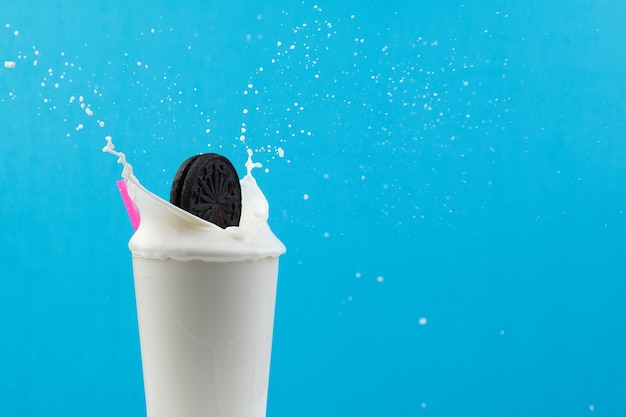 Free photo glass of milk with a pink straw and a cookie splashing