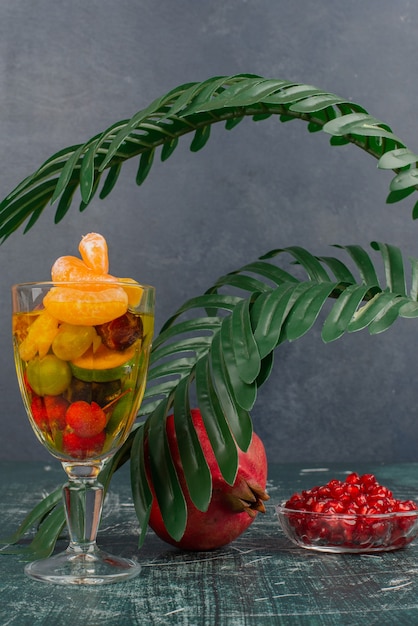 Free Photo glass of mixed fruits and pomegranate with seeds on marble table.