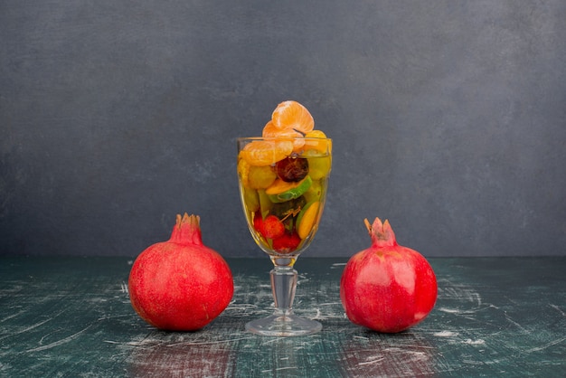 Glass of mixed fruits and pomegranates on marble table.