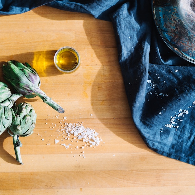 Glass of oil near artichokes and salt