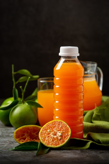 A glass of orange juice and fresh fruit on the floor with ice cubes.