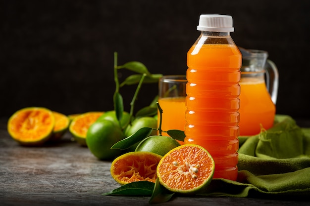 A glass of orange juice and fresh fruit on the floor with ice cubes.