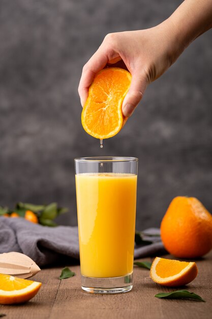 Glass of orange juice and a person squeezing an orange in it