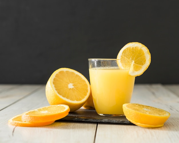 Glass of orange juice and slices of fruit on slate