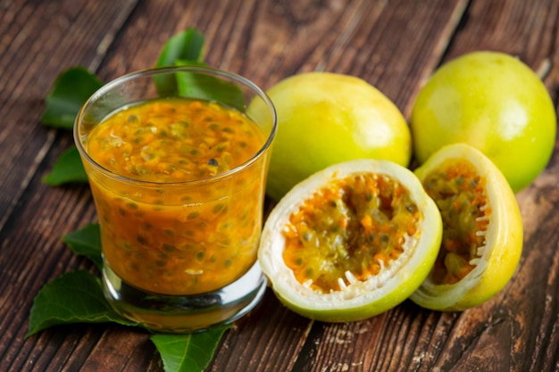 Free Photo a glass of passion fruit juice and fresh passion fruit cut in half place on wooden  floor