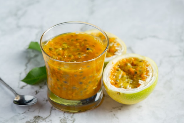 a glass of passion fruit juice place on white marble floor