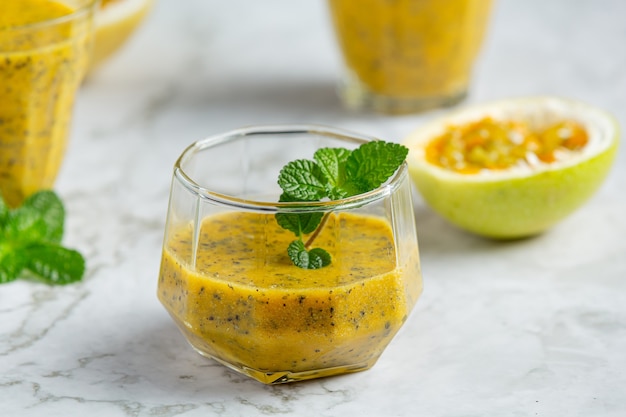 a glass of passion fruit juice place on white marble floor