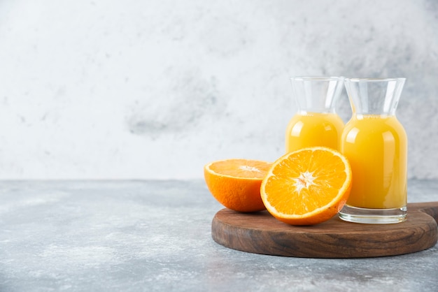 Glass pitchers of juice with slice of orange fruit .