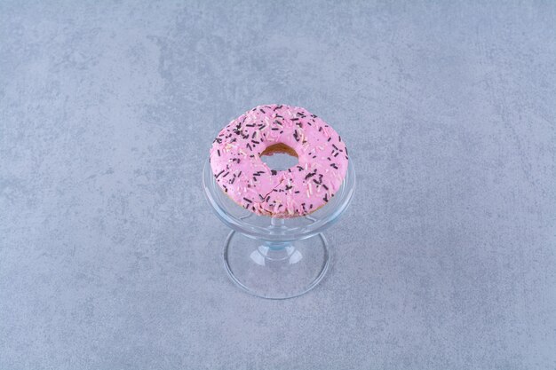 A glass plate of creamy sweet donuts with colorful sprinkles.