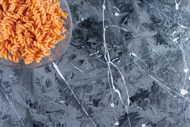 Glass plate of delicious fusilli pasta placed on marble background. 