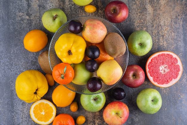 Glass plate of fresh fruits on top of many fruits.