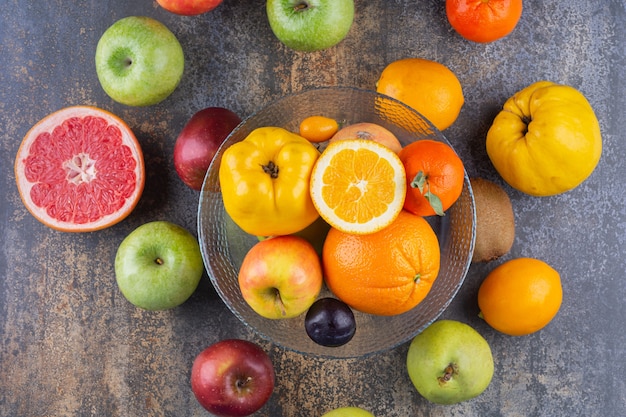 Glass plate of fresh fruits on top of many fruits.