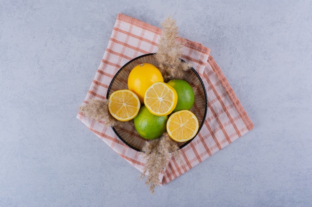 Glass plate of fresh juicy lemons on stone.