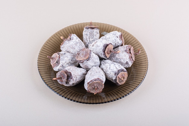 Glass plate full of dried persimmons on white background. High quality photo