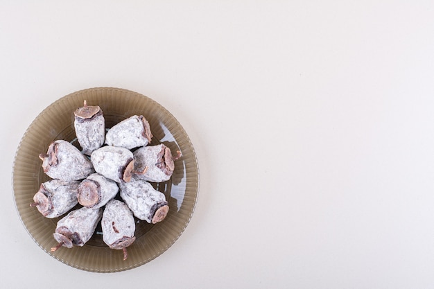 Glass plate full of dried persimmons on white background. High quality photo