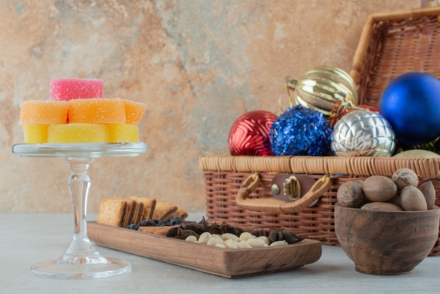 A glass plate full of sugar marmalade and Christmas festive balls on marble background. High quality photo