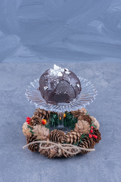 Free photo a glass plate with a chocolate cake and pinecones