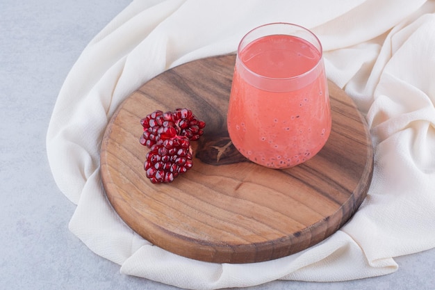 A glass of pomegranate juice on wooden board with seeds. High quality photo