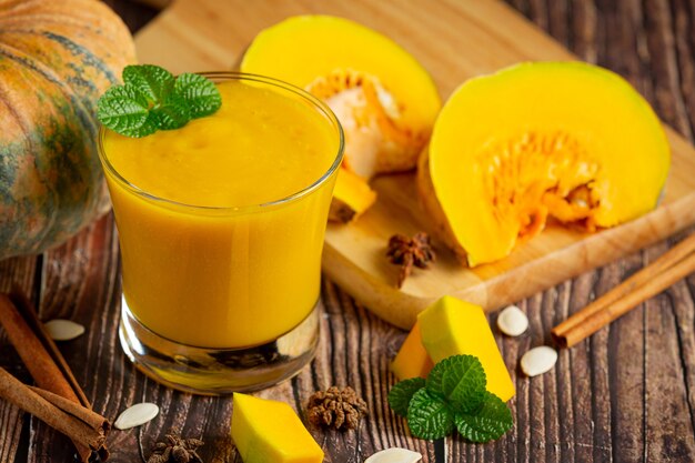 a glass of pumpkin juice and chopped raw pumpkins place on wooden  floor