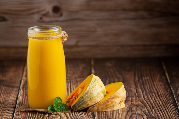 a glass of pumpkin juice and chopped raw pumpkins place on wooden  floor