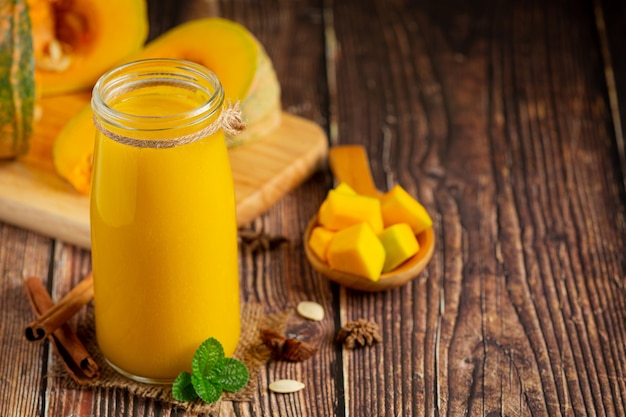 a glass of pumpkin juice and chopped raw pumpkins place on wooden  floor