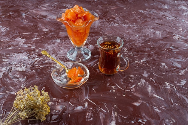 Free photo glass of quince jam and glass of black tea on table.