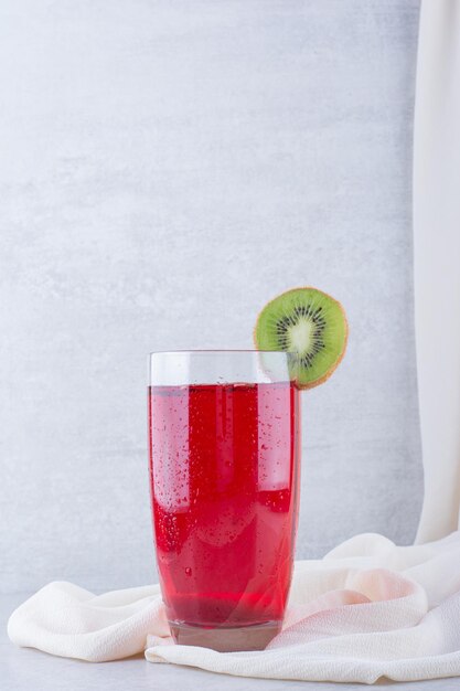 A glass of red juice on tablecloth with kiwi slice. High quality photo