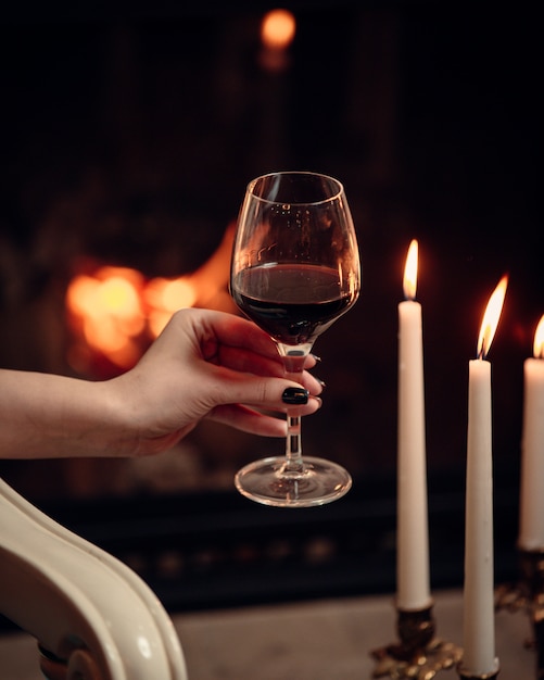 a glass of red wine surrounded with candles in romantic atmosphere