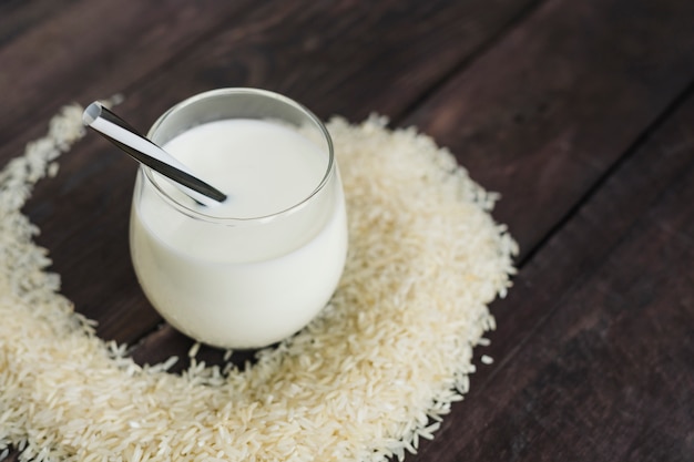 Glass of rice milk with rice grains on wooden table