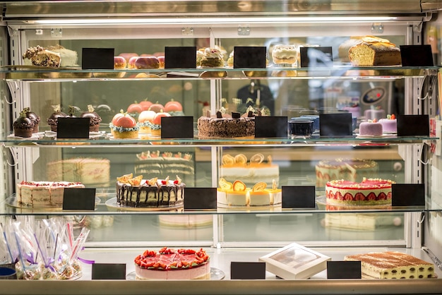 Free photo glass showcase of pastry shop with variety of fresh cakes and pastries. popular sweet desserts offered for sale