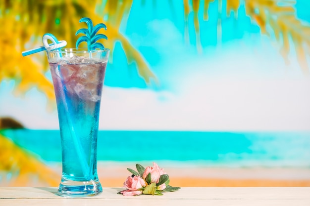 Glass of tasty blue drink and pink flower