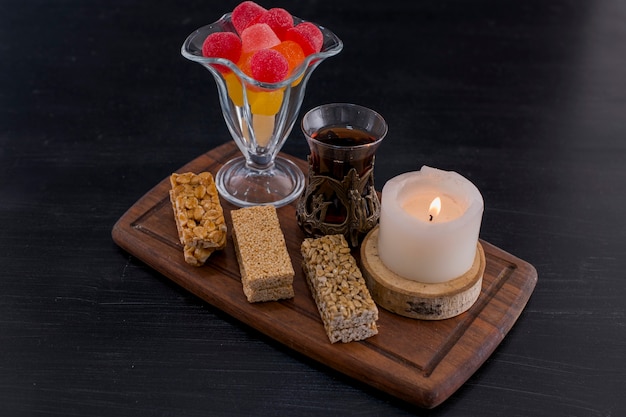 A glass of tea served with marmelades and sesame waffles on blue space