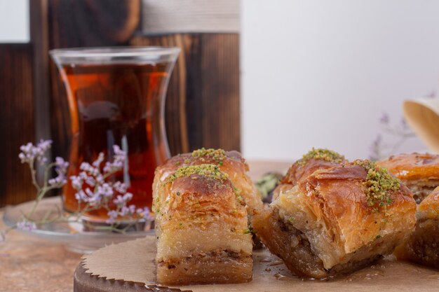 Glass of tea and traditional pistachio baklava on marble table.