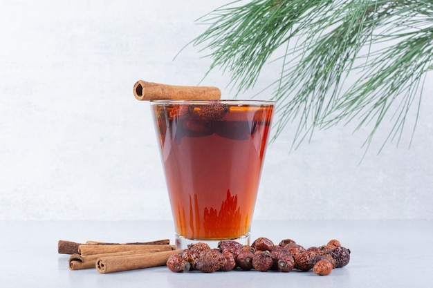 Glass of tea with rosehips and cinnamons on gray background. 