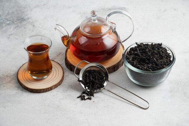 A glass teapot with tea on wooden board.