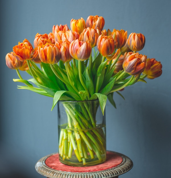 A glass vase of orange color tulips.