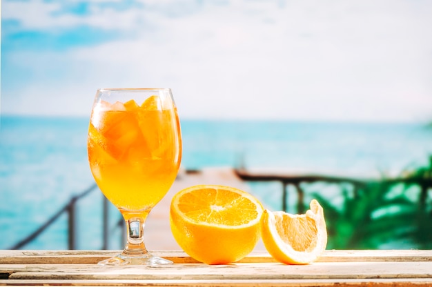 Free photo glass with orange drink and sliced orange on wooden table