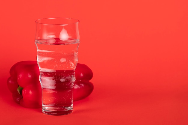 Glass with red pepper and red background