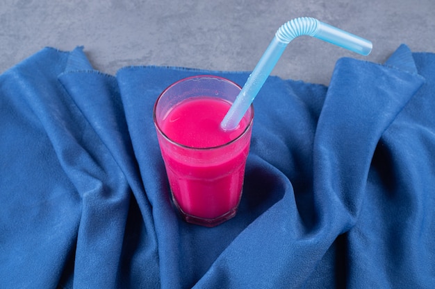 Glass with tasty strawberry smoothie on blue background.