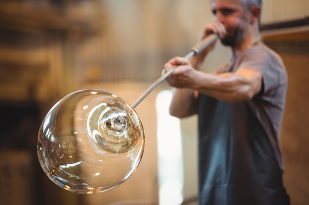 Free Photo glassblower shaping a glass on the blowpipe