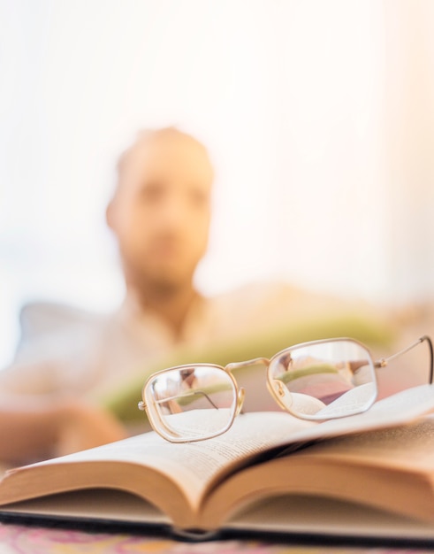 Free photo glasses on book with blurred man in background