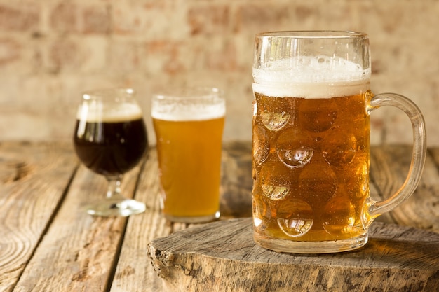 Glasses of different kinds of dark and light beer on wooden table