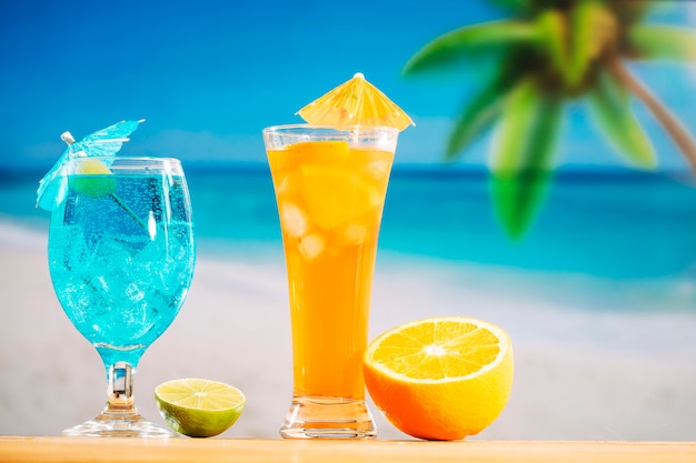 Glasses of fresh drinks decorated with olive umbrella and sliced lime orange