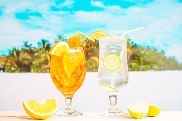 Free photo glasses of juicy orange lemon drinks with straw and sliced citruses