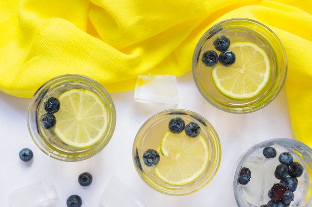 Free Photo glasses of lemon juice with blueberries and ice cubes on white background