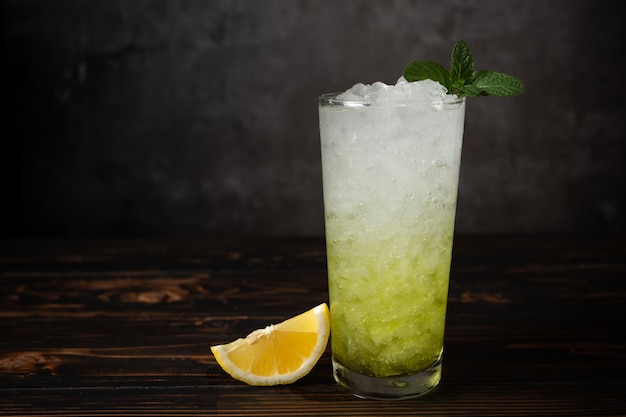 Glasses of lemon soda with ice and fresh mint on wooden table.