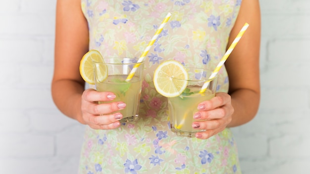 Free photo glasses of lemonade held by a woman